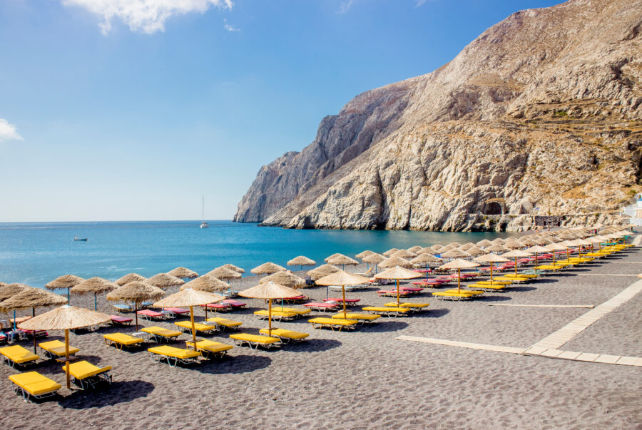 Kamari Beach in Santorini, Greece, featuring black sand, clear blue waters