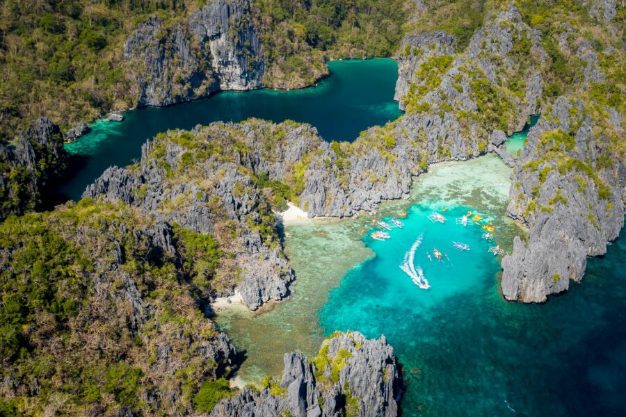 Aerial view of tropical karst limestone islands, turquoise lagoon, and boats.