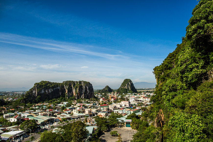 Aerial view of Marble Mountains limestone karst hills rising above a Vietnamese town under blue sky.