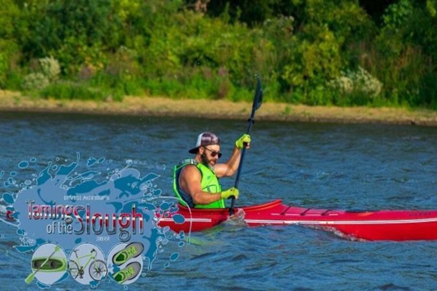 Man kayaking in vibrant red kayak on blue water during Taming of the Slough event.