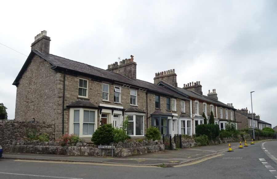 Row of houses at a street corner in Kendal, England, showcasing traditional architecture and a quaint neighborhood.