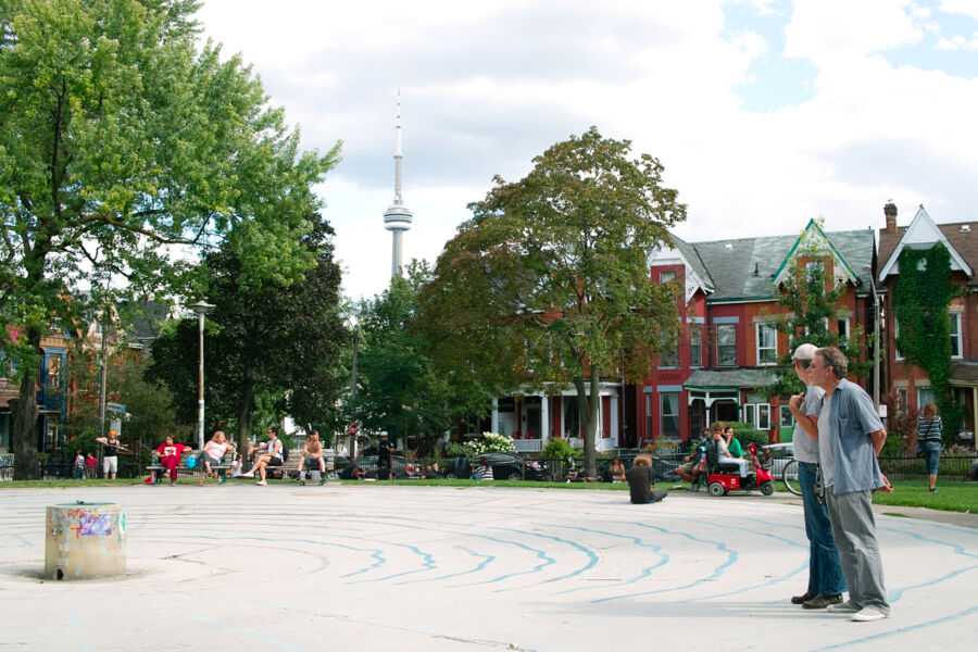 Kensington Market park, Toronto, Canada, with green grass and trees in the background.

