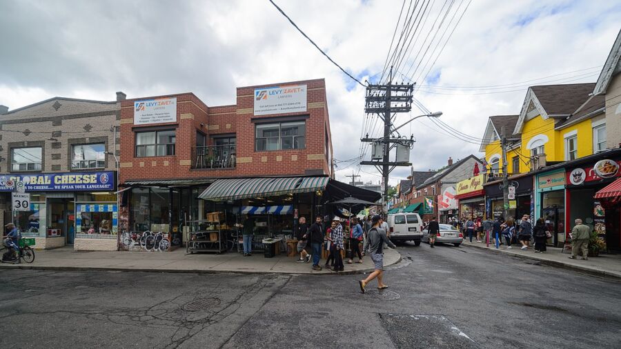 Kensington Market in Toronto, showcasing a lively street scene with numerous shops and pedestrians exploring the area.
