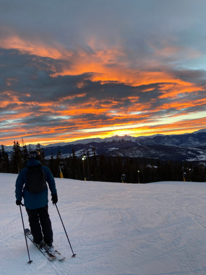 Sunset over Keystone, with skiers gliding down the slopes in the mountains, creating a vibrant winter scene