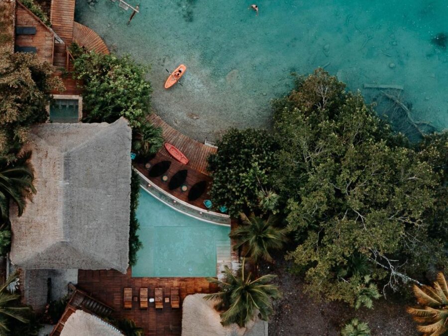 Aerial view of Khaban Bacalar Hotel Boutique, showcasing a pool and beach surrounded by lush tropical scenery.