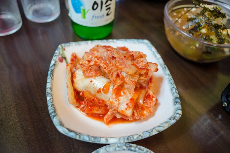Traditional Korean kimchi dish on decorative plate with soda and side dish.