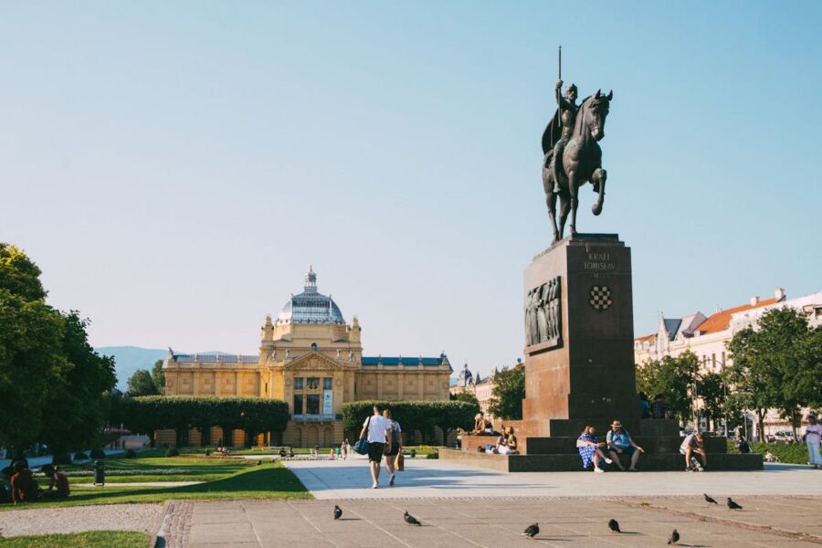 Statue of a historical figure on horseback in a vibrant, sunny urban square.