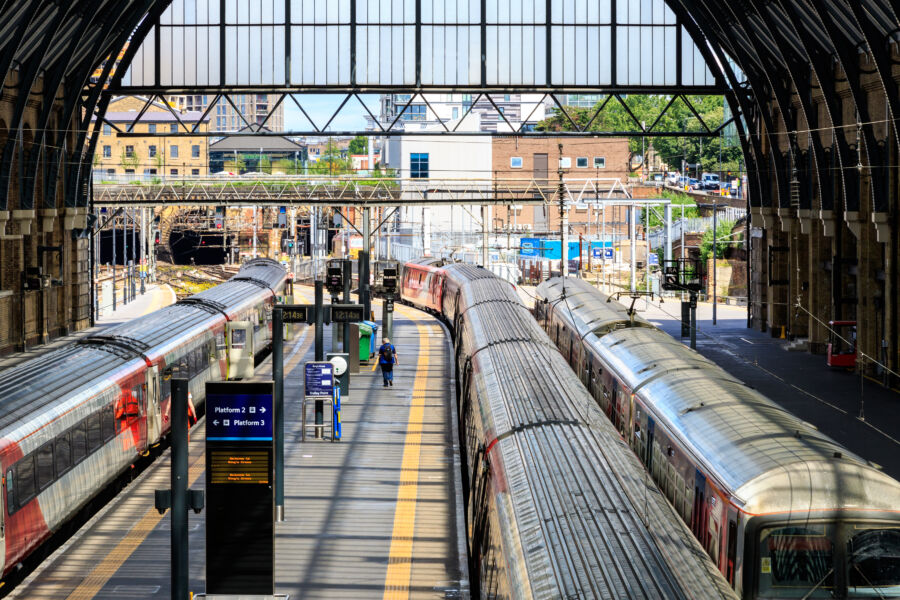 Trains arrive at the platforms of Kings Cross train station, bustling with passengers and activity.