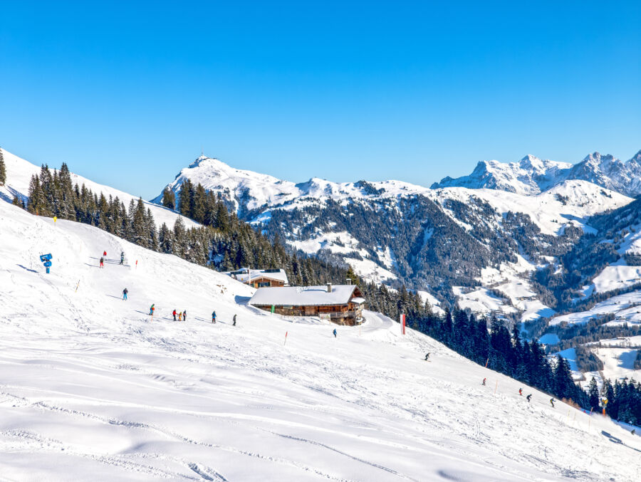 Scenic view of Kitzbuhel ski slope in the Austrian Alps, showcasing snow-covered mountains and skiers enjoying the terrain