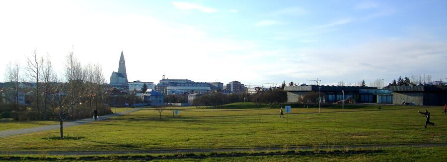 Expansive grassy field in Klambratún Park, Reykjavik, with a building seen far off in the background.