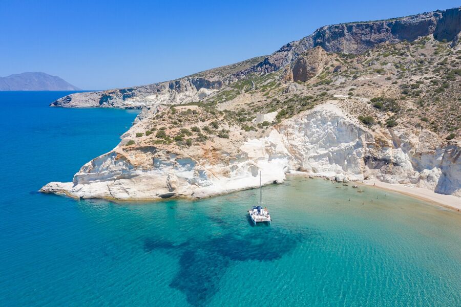 Boat anchored in the clear blue waters of Kleftiko beach on Milos, surrounded by stunning rock formations.