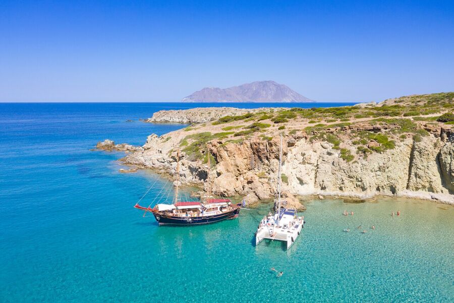 Boat rests in the water by the rocky coastline of Kleftiko on Milos Island, showcasing the area's natural beauty.