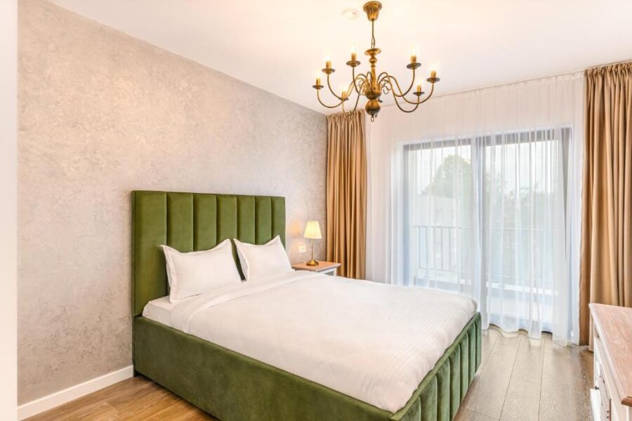 Cozy bedroom in KOA Aparthotel, Brasov, Romania, showcasing a green headboard and a comfortable bed.