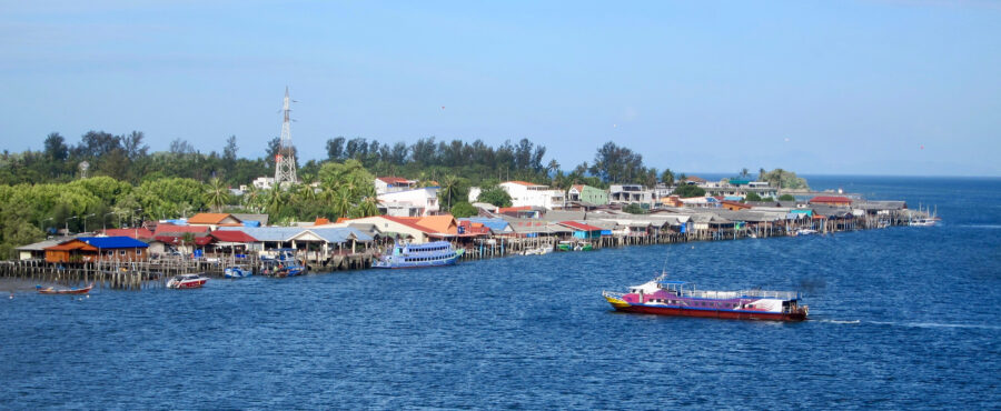 Koh Lanta Thailand coastal village and ferry boat view from bridge over blue tropical sea.