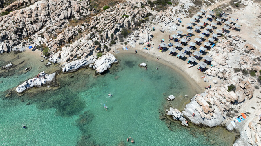 Aerial view of Kolimbithres beach in Naousa, Paros, showcasing unique rock formations and organized sandy areas.