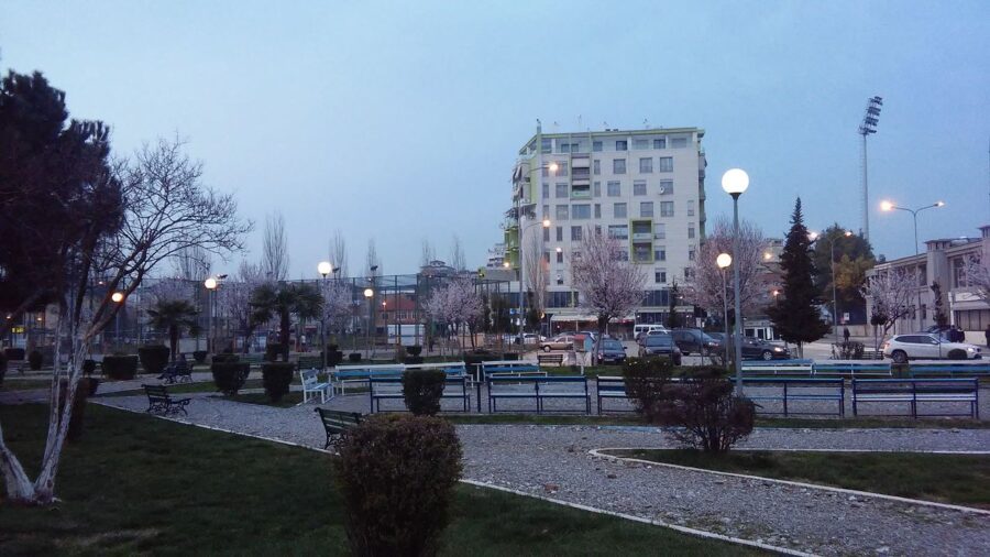 Urban park at twilight featuring bare trees and lit street lamps in Komuna e Parisit Tirana.