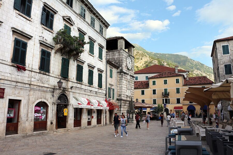 People strolling down Kotor's Piazza of the Arms, enjoying the lively atmosphere and beautiful architecture of the city.