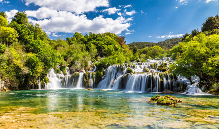 Scenic view of Krka Waterfalls in Krka National Park, Croatia, showcasing cascading water and lush greenery.
