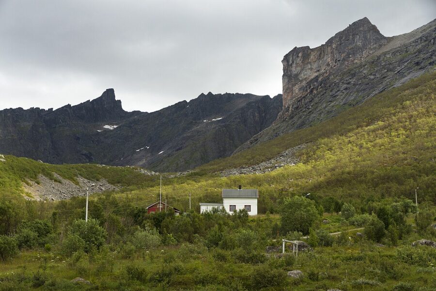 Quaint house located in the mountainous landscape of Kvaløya, Norway, showcasing the serene wilderness.
