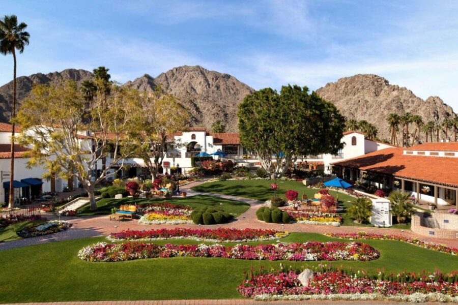Lush gardens at La Quinta Resort & Club, showcasing vibrant flowers and palm trees under a clear blue sky.

