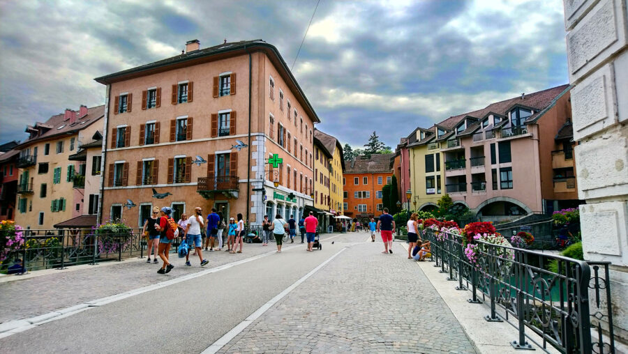 People walking down a narrow street in La Vieille Ville, Annecy, surrounded by historic buildings and charming architecture.