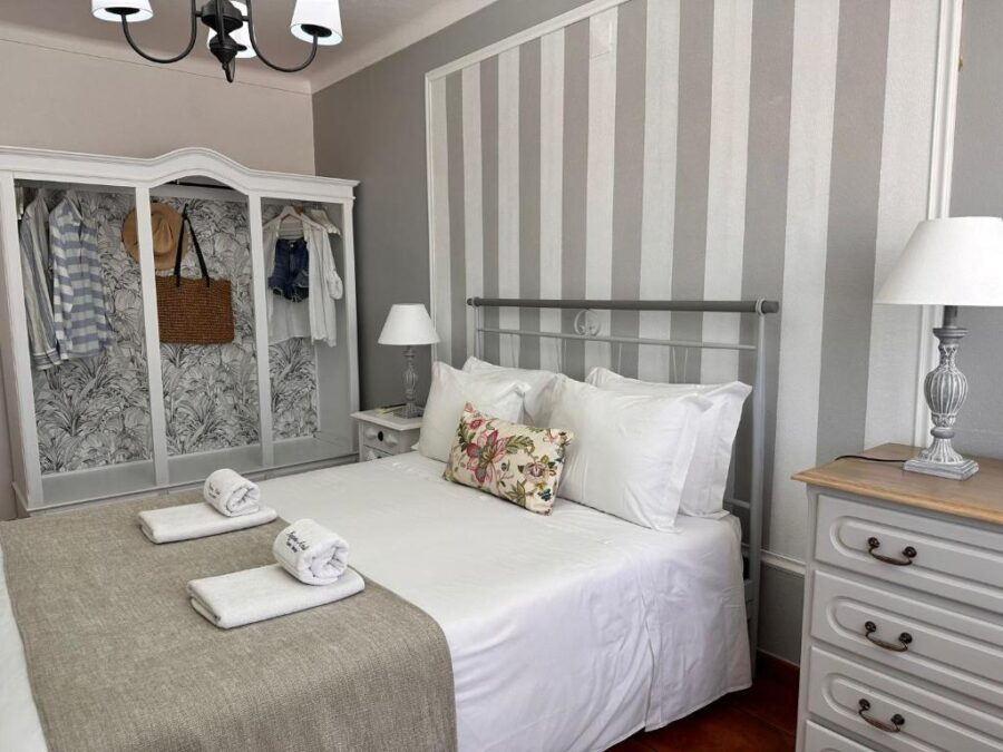 Cozy bedroom in Lagoa Azul guest house, Portugal, featuring striped walls and a bed with crisp white sheets.