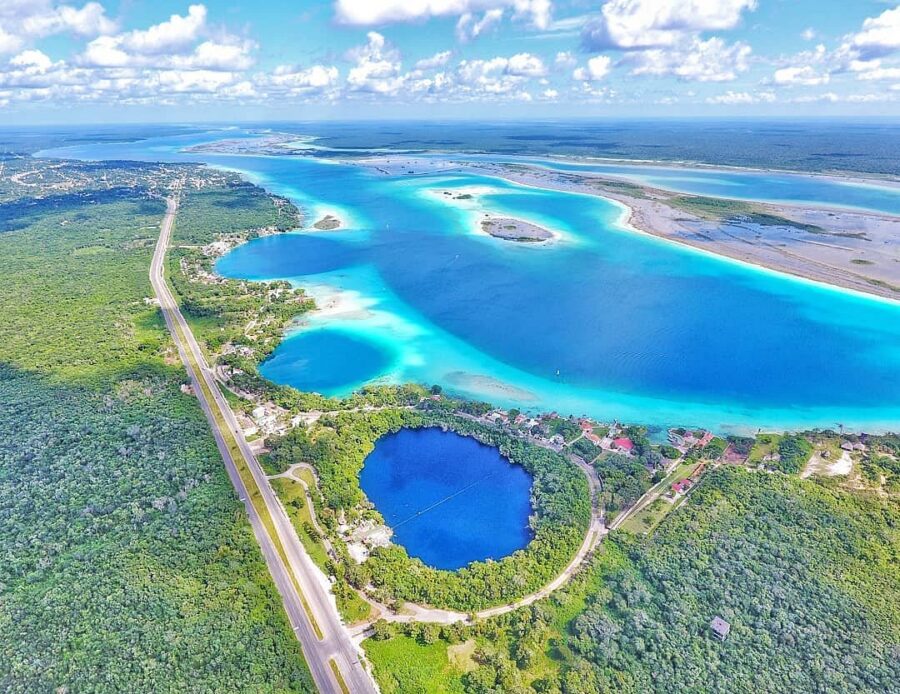 The blue lagoon of Laguna de Bacalar, a stunning natural wonder in Quintana Roo, Mexico, surrounded by lush greenery.