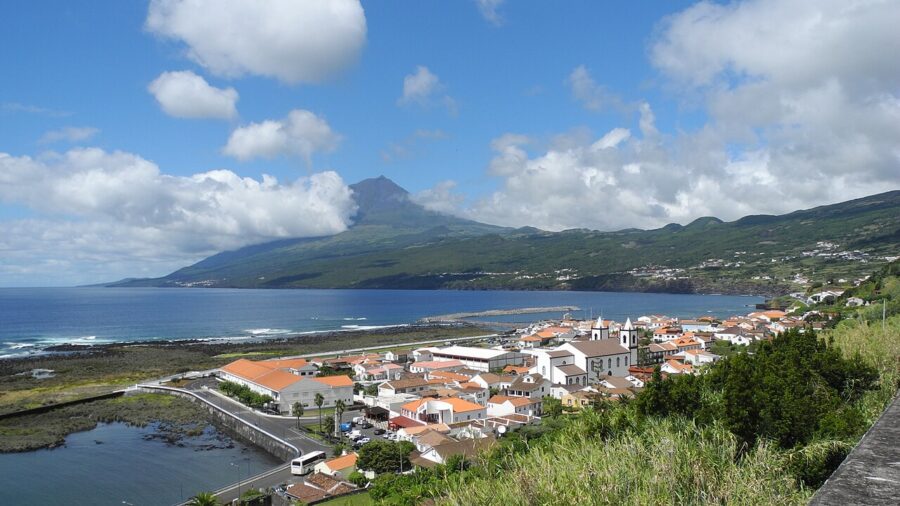 Coastal view of Lajes do Pico, Portugal, featuring a town with a mountain backdrop.
