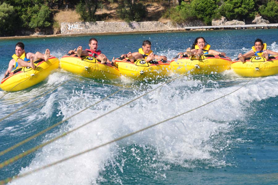 Group enjoying thrilling lake water tubing ride under sunny skies.