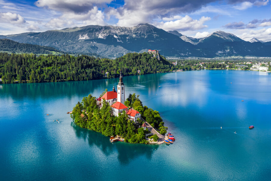 Aerial view of Lake Bled, featuring the Pilgrimage Church and pletna boats on the serene blue water