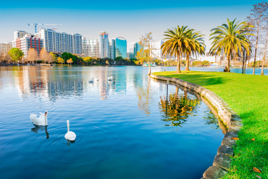 Scenic view of Lake Eola Park in Orlando, Florida, featuring a serene lake surrounded by lush greenery and city skyline.