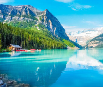 Stunning landscape of Lake Louise in Banff National Park, featuring vibrant blue water framed by towering peaks and greenery.