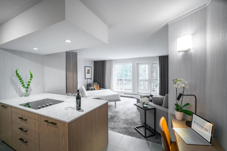 Modern Lake Louise Inn room featuring a cozy bed and a stylish kitchen area.
