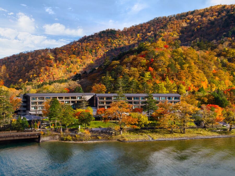 Lakeside autumn mountain resort hotel with colorful fall foliage, tranquil water, and modern architecture.