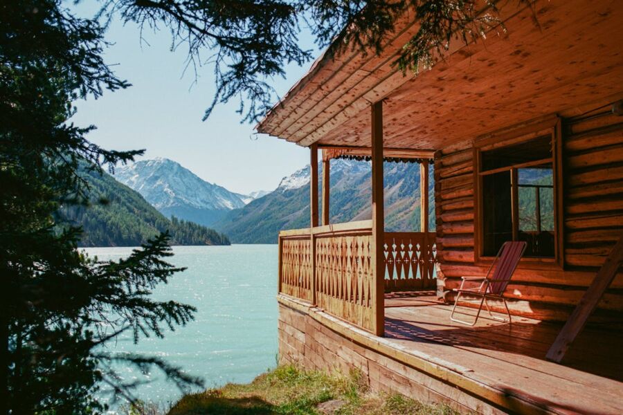 Rustic lakeside cabin with mountain views and serene waters reflecting the sky.