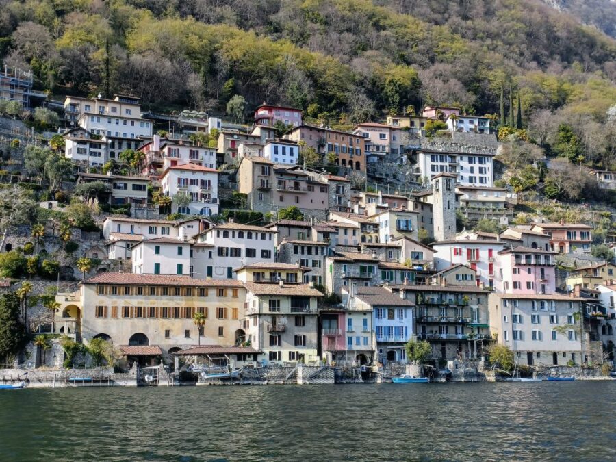 Gandria lakeside village with terraced colorful houses, boats, and stone waterfront on steep hillside.