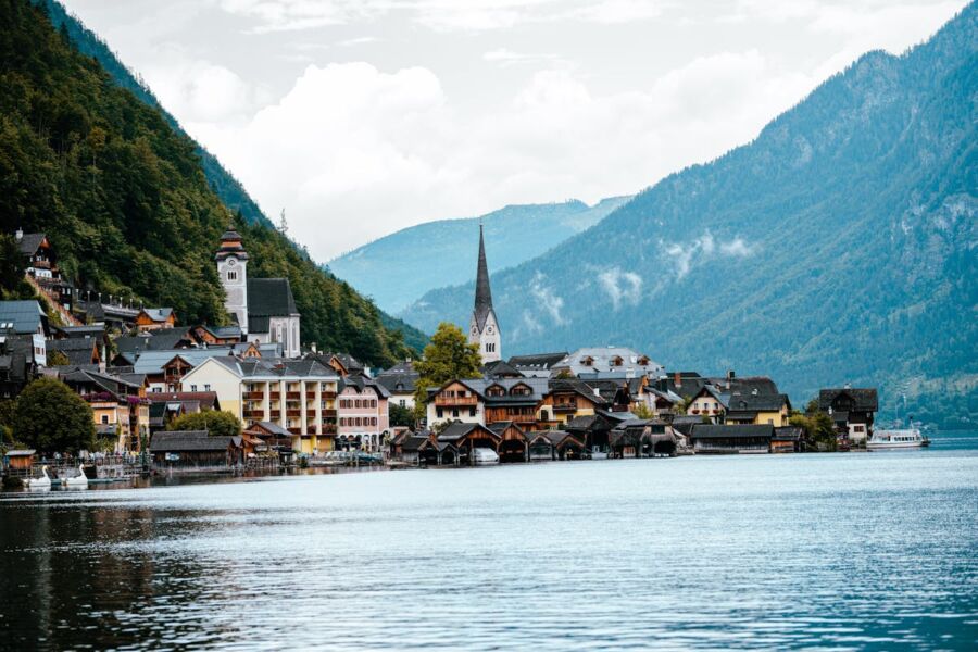 Charming lakeside village with colorful Alpine houses, mountains, and a serene reflecting lake.