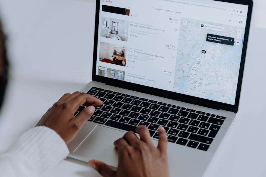 Searching Airbnb for accommodations on a laptop, displaying listings and map for travel planning.