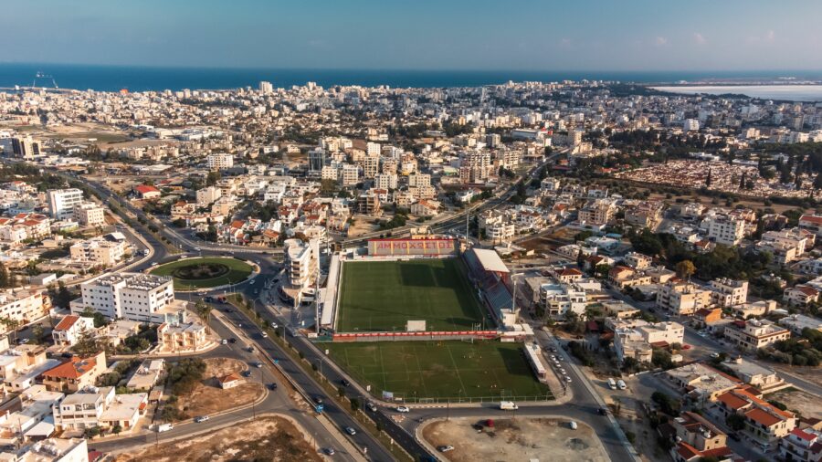 Aerial view of Larnaca, Cyprus, showcasing a coastal cityscape with a prominent football stadium.