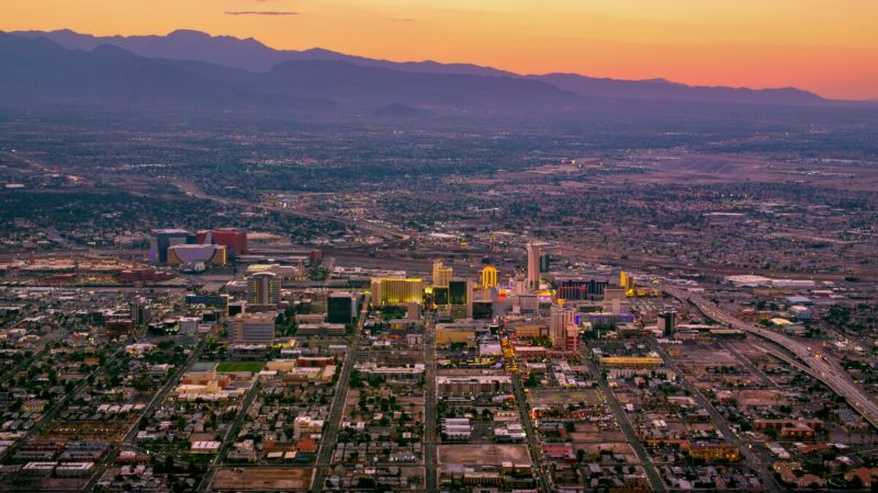 Aerial view of Las Vegas cityscape at sunset with mountains and vibrant skyline.