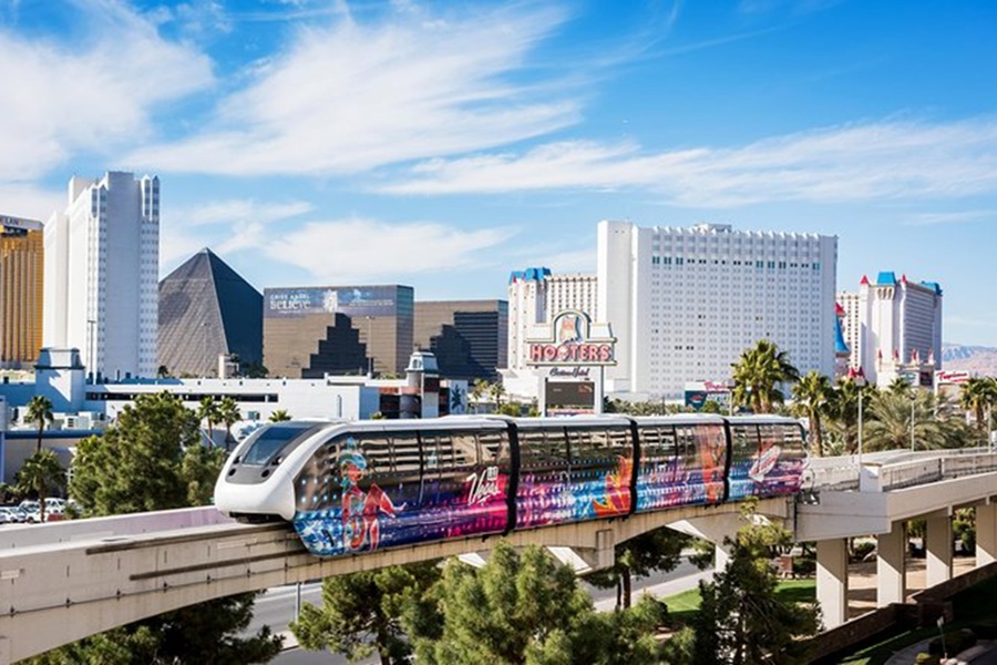 Futuristic Las Vegas monorail with vibrant graphics glides above the bustling Strip and landmarks.