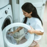 A Woman Wearing a White Shirt Doing a Laundry Kneeling