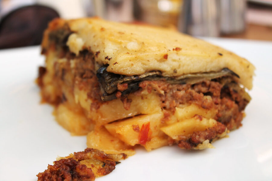 Traditional Greek moussaka slice with layers of meat, eggplant, potatoes, and golden béchamel crust.