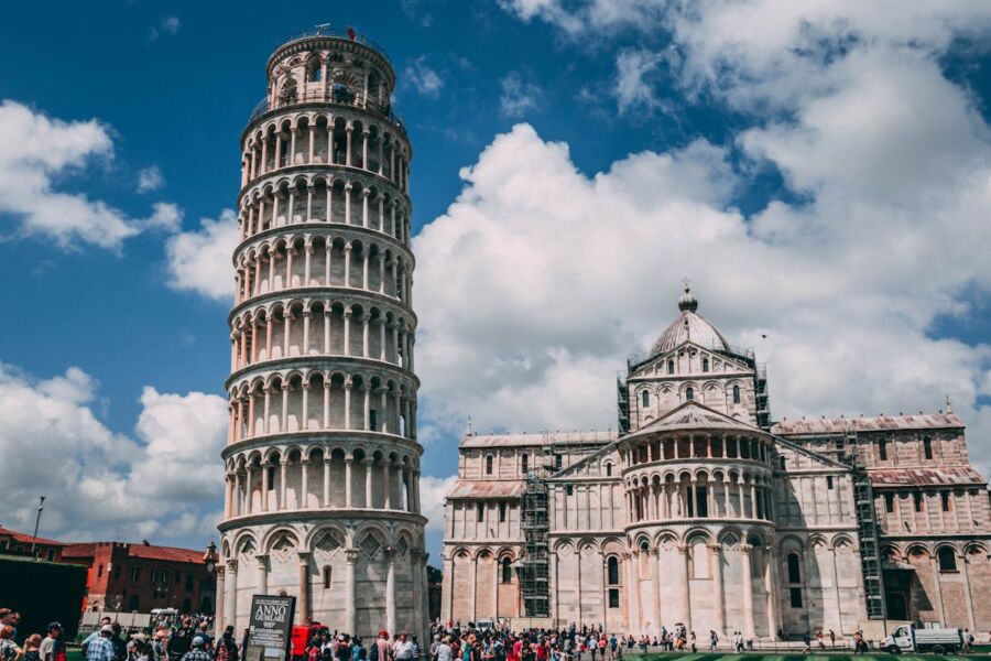 Leaning Tower of Pisa with Pisa Cathedral in background, iconic Italian landmarks, tourists visiting.