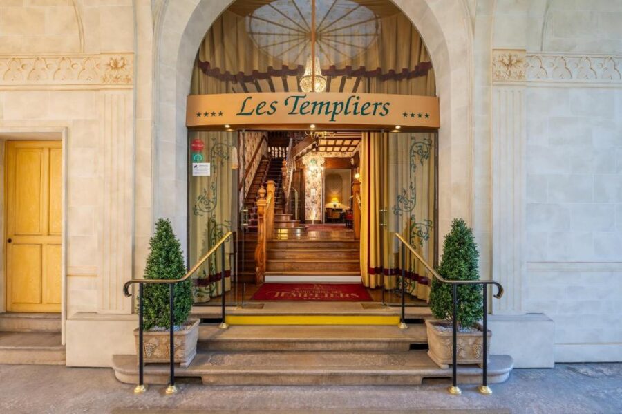 Les Templiers boutique hotel stone-arched entrance with gold canopy and warm wood interior.