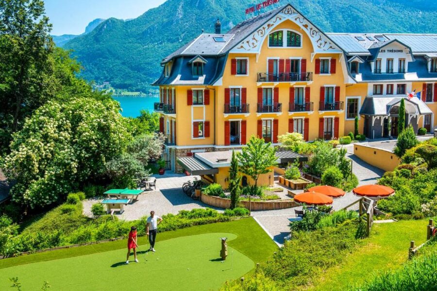 Scenic view of Les Trésoms Lake and Spa Resort, nestled between a tranquil lake and towering mountains in Annecy.