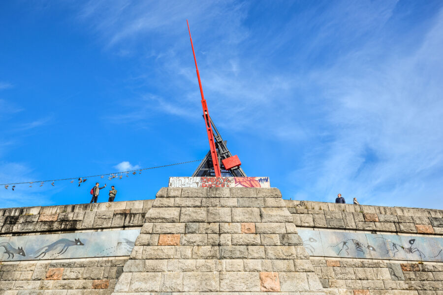 The Prague Metronome, a giant structure in Letná Park, towers over the Vltava River, representing rhythm and time