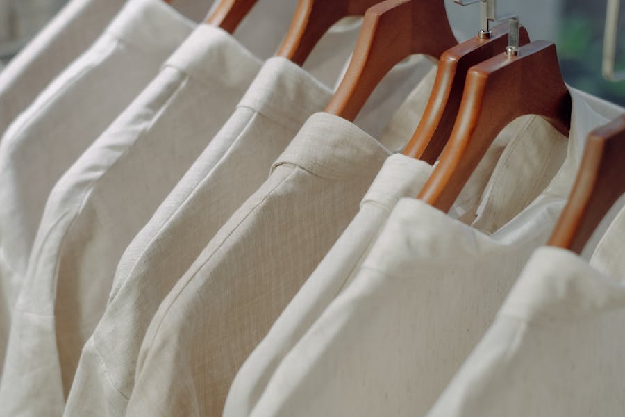 Light-colored shirts on wooden hangers in a minimalist, elegant display.