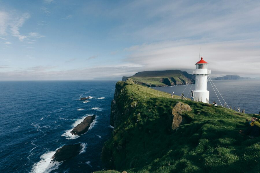 Mykines Faroe Islands lighthouse on rugged grassy cliff overlooking ocean.