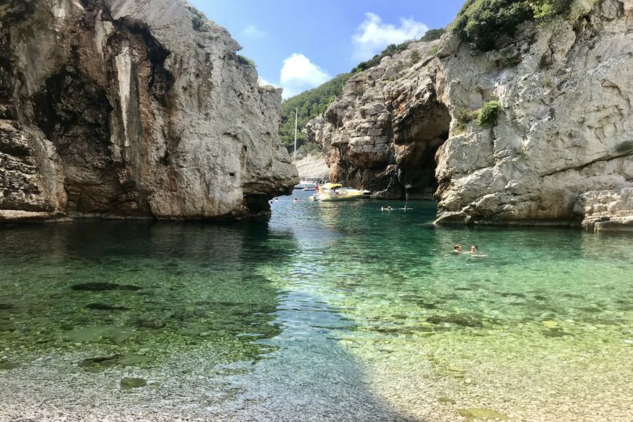 Stiniva Beach limestone cove with crystal-clear turquoise water and swimmers in secluded Croatian inlet.